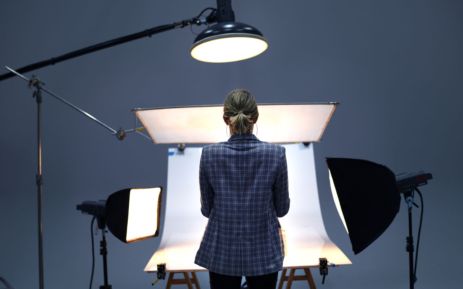 Rückansicht einer Fotografin, die vor einer Hohlkehle steht, welche von mehreren Scheinwerfern beleuchtet wird.