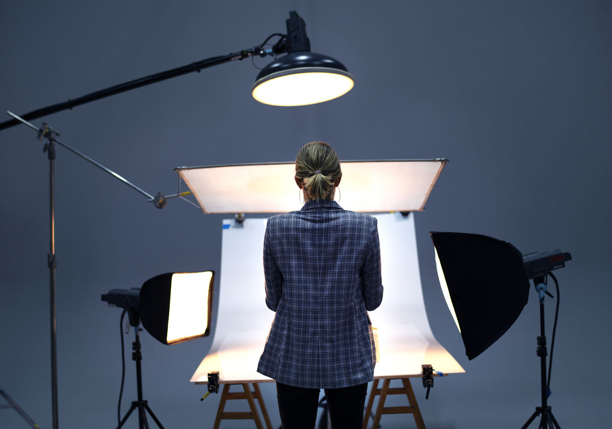 Rückansicht einer Fotografin, die vor einer Hohlkehle steht, welche von mehrern Scheinwerfern beleuchtet wird.